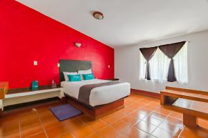 a bedroom with a large bed with a red wall at Ayenda Mesón del Río in Tepotzotlán