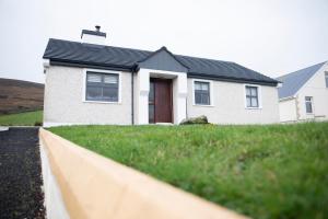 a white house with a black roof at 3 Bed Renovated Cottage Carramore Lake, Belmullet in Ballina