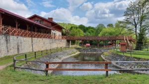 a wooden bench sitting next to a river with a bridge at Camper Park Radków - domki i pokoje in Radków