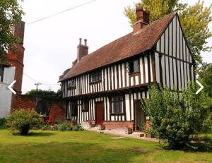 an old black and white house with arrows pointing toward it at Bonnington Cottage by Bloom Stays in Canterbury