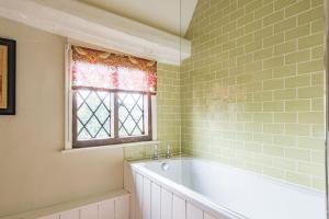 a bathroom with a bath tub and a window at Bonnington Cottage by Bloom Stays in Canterbury +14 photos