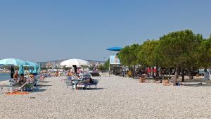 a beach with people sitting on chairs and umbrellas at STUDIO APARTMANI KIKI in Srima