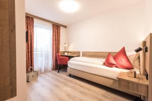Habitación de hotel con cama con almohadas rojas en Pension Rofan, en Reith im Alpbachtal