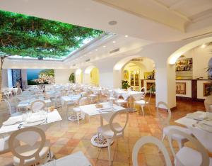 a restaurant with white tables and white chairs at Villa Romana Hotel & Spa in Minori