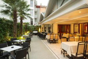 an outdoor restaurant with tables and chairs and palm trees at Hotel Imperia in Lido di Jesolo
