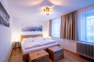 Schlafzimmer mit einem Bett mit weißer Bettwäsche und einem Fenster in der Unterkunft Bergzeit Appartments in Bad Gastein