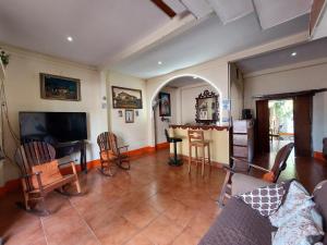 a living room with a couch and a tv and chairs at Hostal Ruinas de San Sebastián in León