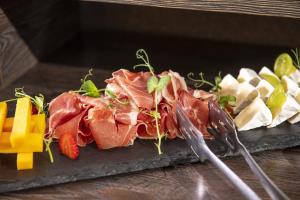 a plate of food with meat and cheese at Session Hotel Ráckeve in Ráckeve