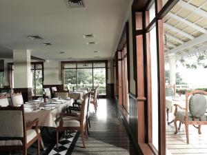 a dining room with tables and chairs and windows at The Gateway Hotel Pasumalai Madurai in Madurai