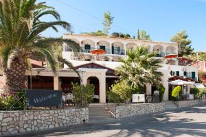 un grand bâtiment blanc avec des palmiers devant lui dans l'établissement Hotel Apollon Corfu, à Paleokastritsa