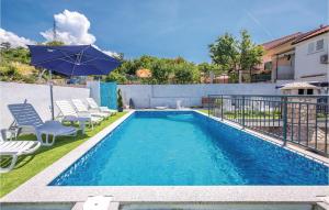 a swimming pool with chairs and an umbrella at Cozy Apartment In Crikvenica With Wifi in Crikvenica