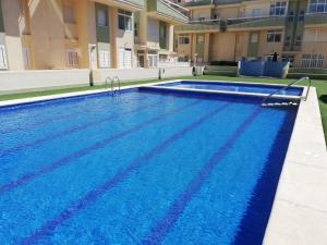 a swimming pool with blue water in a building at Delfines III Solo Familias Serviplaya in Playa de Xeraco