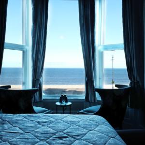a bedroom with a bed and a view of the ocean at Glan Y Mor Hotel (Adult Only) in Llandudno