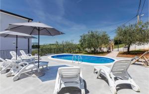 a group of chairs and an umbrella next to a pool at 2 Bedroom Stunning Apartment In Porec in Dračevac