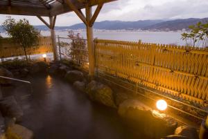諏訪市にあるRako華乃井ホテルの木製の柵と湖のある水のプール
