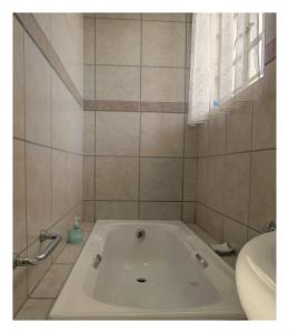 a white tub in a bathroom with a window at Alte Welkom Guesthouse in Klerksdorp