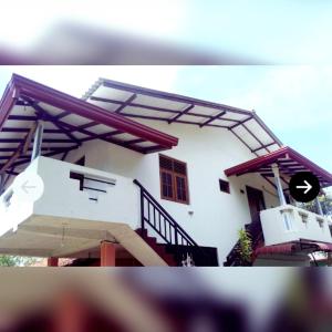 ein weißes Haus mit einer Treppe davor in der Unterkunft Deshan Homestay & Restaurant in Tangalle