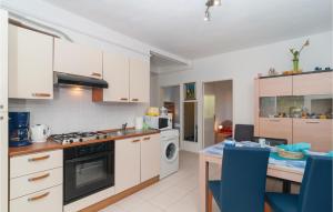 uma cozinha com armários brancos e uma mesa com cadeiras azuis em Amazing Apartment In Supetar With Kitchen em Supetar