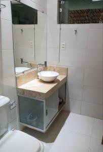 uma casa de banho com um lavatório, um espelho e um WC. em Flat Recanto do Sertão em Piranhas