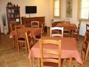 a dining room with tables and chairs and a tv at Alojamiento Rural La Henera in San Juan de Ortega