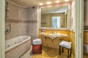a bathroom with a tub, sink, toilet and bathtub at Romano Palace Luxury Hotel in Catania