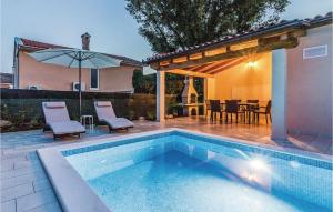 basen w ogrodzie ze stołem i parasolem w obiekcie Holiday Home Medulin Ii w Medulinie