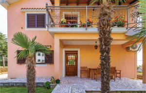 a house with a balcony and a table and palm trees at 2 Bedroom Cozy Apartment In Rubesi in Rubeši