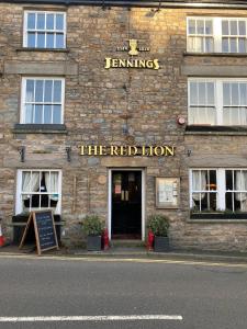 a stone building with a red lion sign on it at The Red Lion in Sedbergh