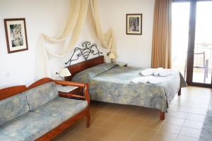 a hotel room with two beds and a couch at Areti Aparthotel in Áptera