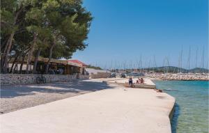 a walkway next to a beach with boats in the water at One-Bedroom Apartment In Jezera in Jezera