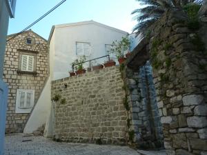 a stone wall and a white building with a palm tree at Apartment Old Town Design in Rab