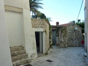 a stone building with a door and a palm tree at Apartment Old Town Design in Rab +9 photos