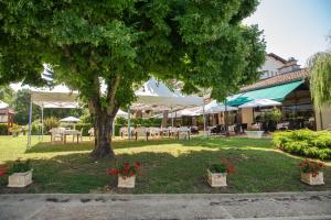 un parque con un árbol, mesas y sillas en Logis Hôtel et Restaurant La Bombardière, en Cuq-Toulza