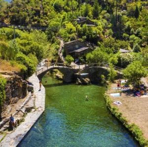 a river with a bridge and people in the water at Casa Do Bispo pereiro,Arganil in Coimbra