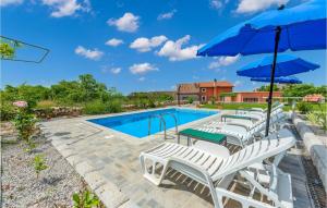 a pool with white lounge chairs and blue umbrellas at Beautiful Home In Labin With 3 Bedrooms, Wifi And Outdoor Swimming Pool in Labin