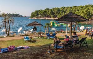 a group of people sitting in lawn chairs at a beach at Amazing Apartment In Porec With 2 Bedrooms And Wifi in Poreč