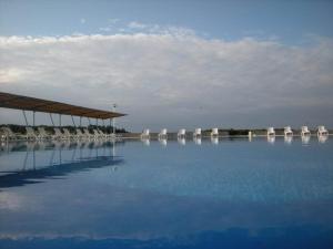 una gran piscina de agua con sillas y mesas blancas en Bazeni Baikal en Topola