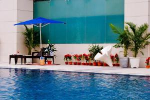 a swimming pool with a blue umbrella and some plants at Ramada Jamshedpur Bistupur in Jamshedpur