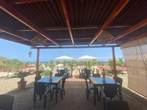 un patio con mesas, sillas y sombrillas en El Samay Hotel Boutique en Canoas de Punta Sal