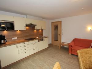 ウダーンスにあるStylish Apartment in Uderns with Balconyの白いキャビネットと赤いソファ付きのキッチン