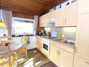 eine Küche mit weißen Schränken, einem Tisch und einem Waschbecken in der Unterkunft Comfy Chalet in Niedernsill with Fireplace in Niedernsill