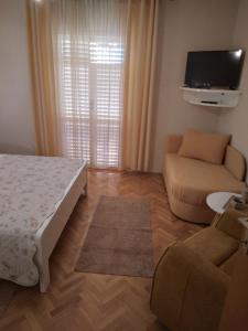 a bedroom with a bed and a couch and a tv at Apartments Panorama view Zeljko Scerbe in Rab