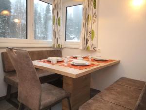 キルヒベルク・イン・チロルにあるPicturesque Holiday Home with Terrace in Kirchbergのダイニングルームテーブル(椅子2脚、テーブル、皿、カップ付)