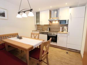 eine Küche mit einem Holztisch und eine Küche mit weißen Schränken in der Unterkunft Spacious Apartment in Kleinarl near Ski Lift in Kleinarl