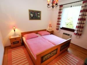 Schlafzimmer mit einem Bett mit rosa Bettwäsche und einem Fenster in der Unterkunft Holiday apartment in Ferlach near Woerthersee in Oreinschnak