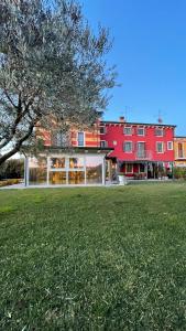 un edificio rosso con un campo verde davanti di Corte Caselle a Sommacampagna