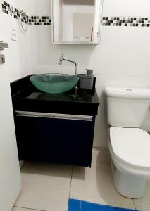 uma casa de banho com um lavatório verde e um WC em Apartamento Praia Grande Vila Caiçara na Praia Grande