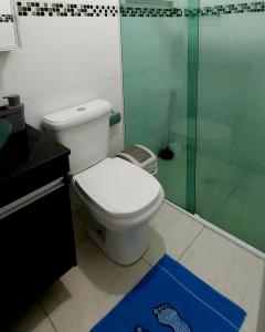 uma casa de banho com um WC e uma cabina de duche em vidro. em Apartamento Praia Grande Vila Caiçara na Praia Grande