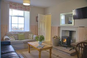 ein Wohnzimmer mit Couch und Kamin in der Unterkunft Powillimount Cottage in Kirkbean