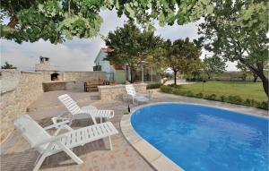 a pool with white chairs and a table and a house at Amazing Home In Nadin With Jacuzzi, Wifi And Outdoor Swimming Pool in Nadin